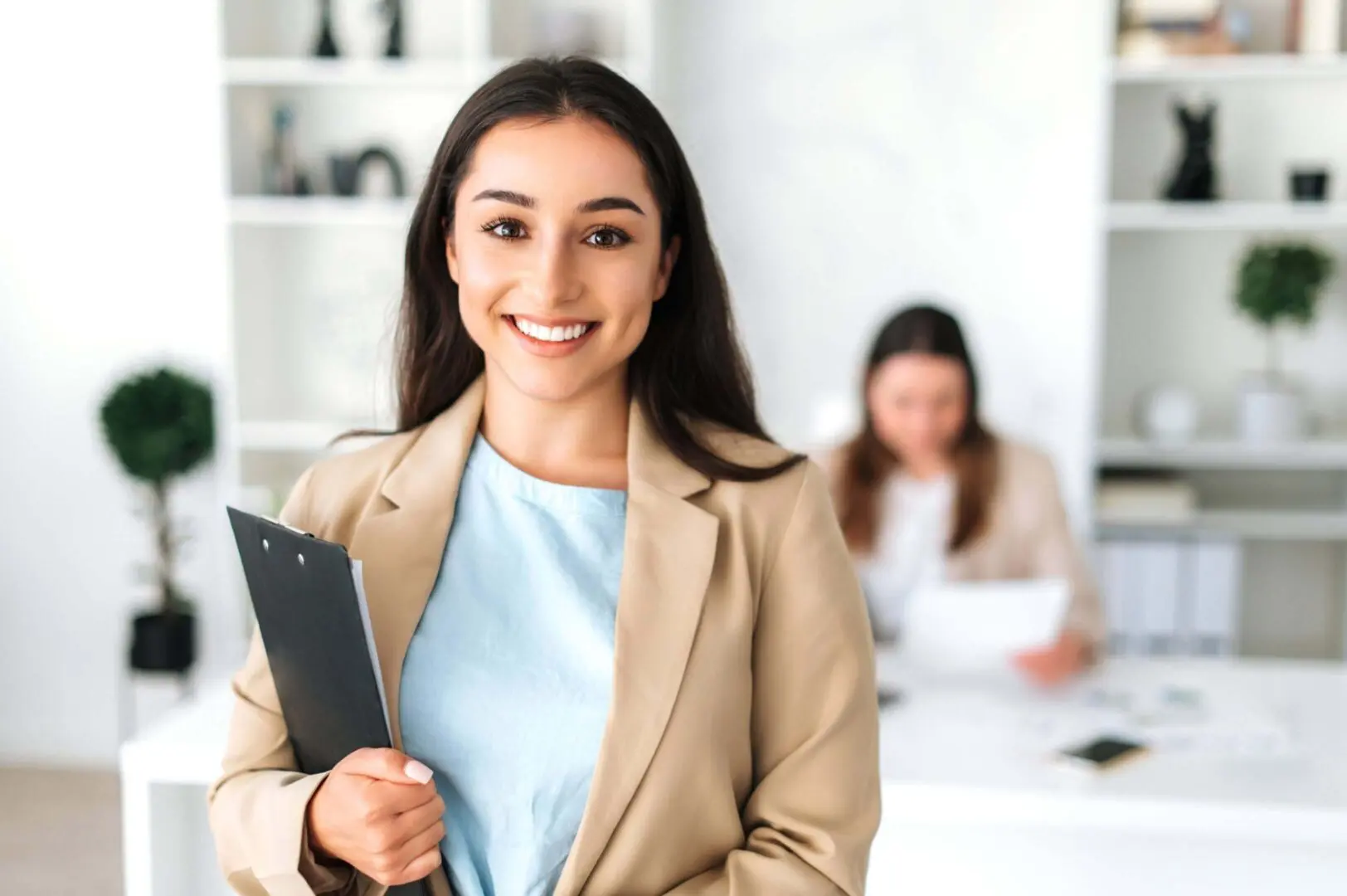 Confident businesswoman holding a clipboard and smiling at the camera.