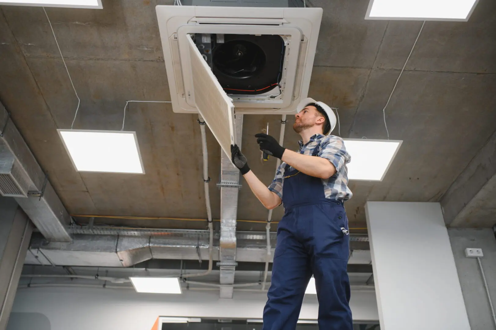 Technician servicing ceiling air conditioning cassette unit